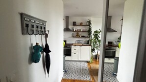 Eine moderne Küche mit weißen Schränken, einer Edelstahl-Dunstabzugshaube und einem gemusterten Teppich.