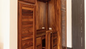 A wooden closet with multiple compartments and drawers, a tiled floor, and a door in the background. - Inn on the Park (Quepos)