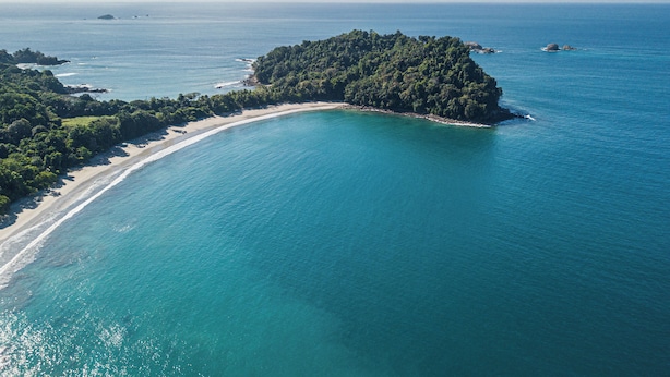 An aerial view of a tropical island with a beach and clear blue waters. - Inn on the Park (Quepos)