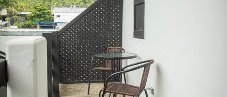 A balcony with a table and chairs, a black lattice partition, and a window with a sign.