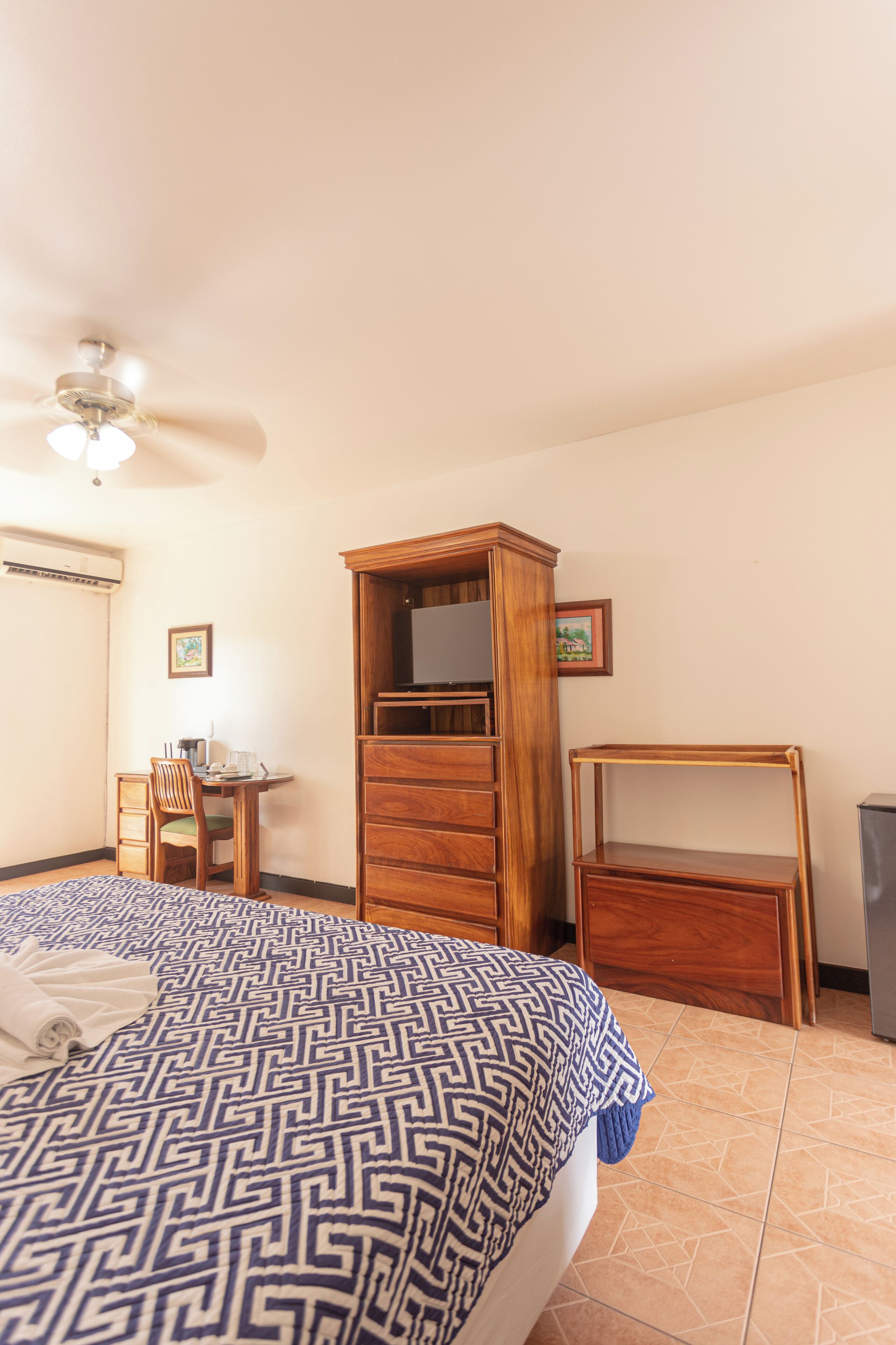 Une chambre à coucher avec un lit, une armoire en bois, un bureau et une chaise.