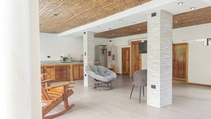 A spacious living area with a high ceiling, wooden flooring, and modern furniture including a rocking chair and two chairs. - Inn on the Park (Quepos)