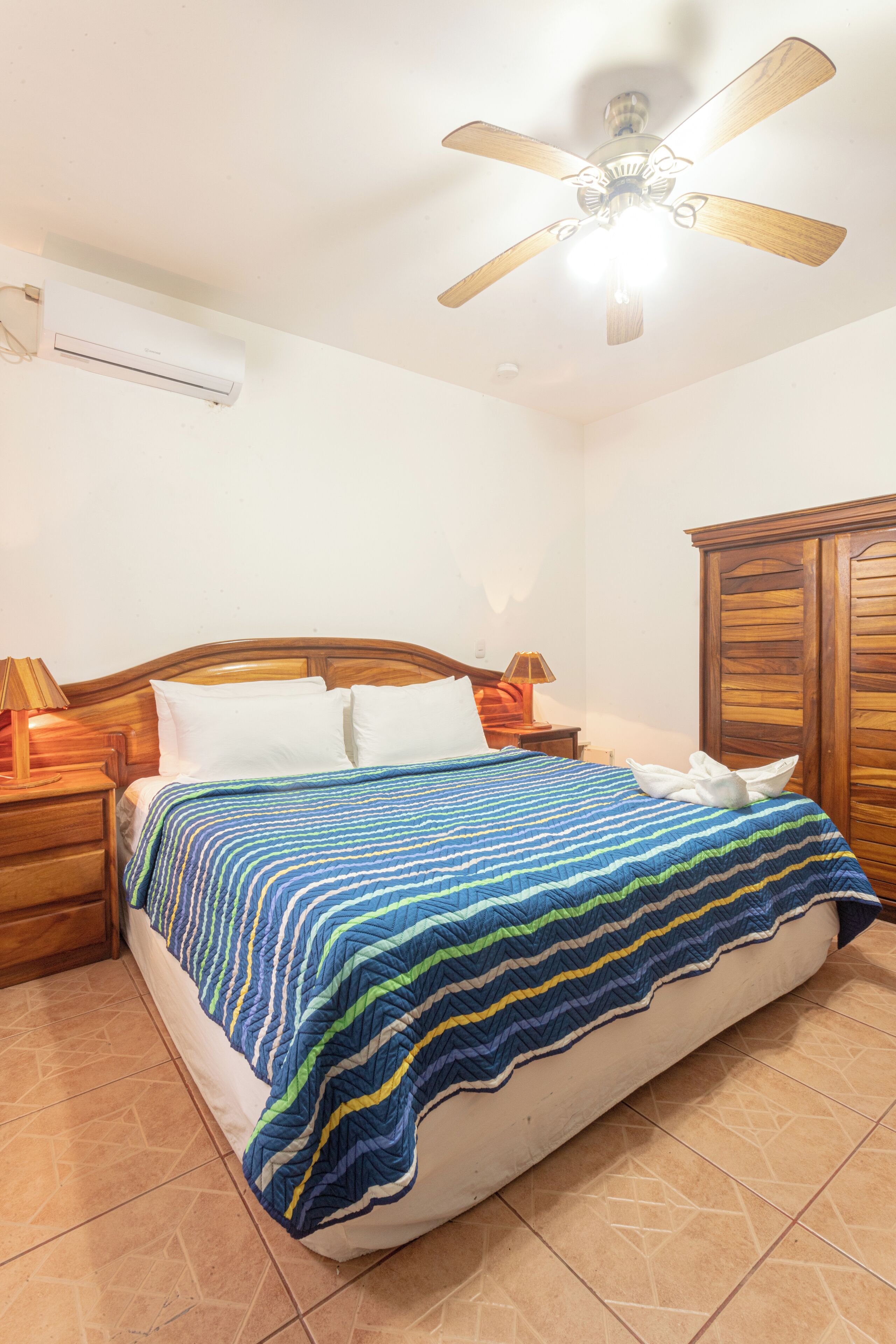 Camera da letto con un letto, una testiera in legno, comodini, una ventola a soffitto e un armadio.