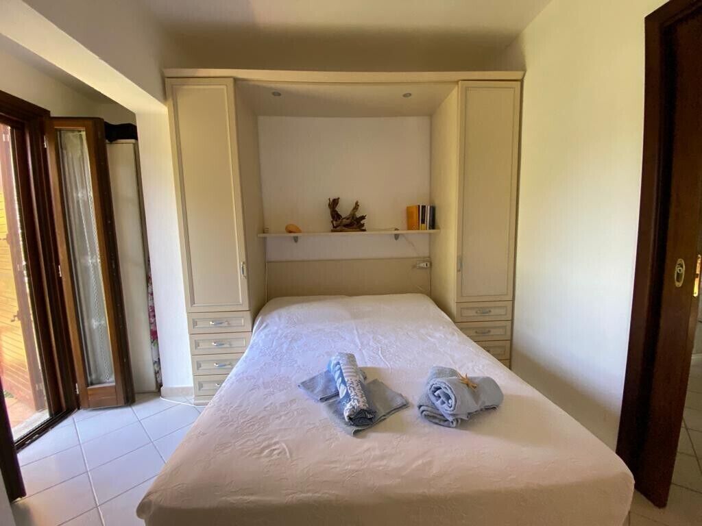 Ein Schlafzimmer mit Bett, Kleiderschrank, Ablagefläche und einer Tür.