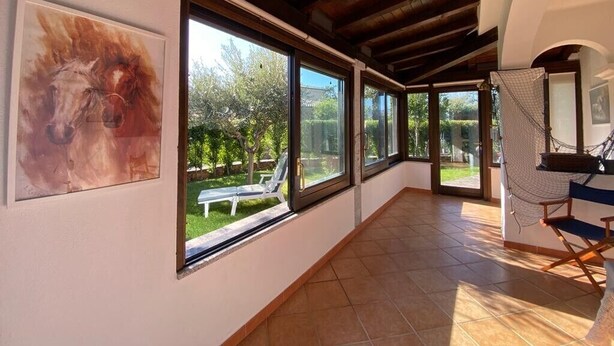Una habitación amplia con ventanas grandes, una hamaca y un sillón de director.