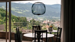 A balcony with a table and chairs, a hanging light fixture, and a view of a town and mountains. - Apartment 'Cityview Apt 1' with Mountain View, Private Terrace and Wi-Fi (Bressanone)