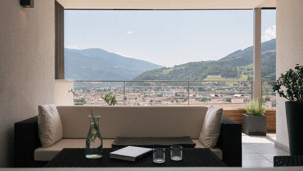 A balcony with a sofa, a vase, and two glasses.