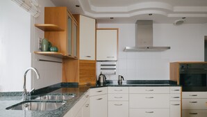 A modern kitchen with a built-in oven, stainless steel sink, and wooden cabinets.