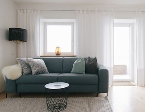 Un salon moderne avec un canapé, une table basse ronde et un lampadaire.
