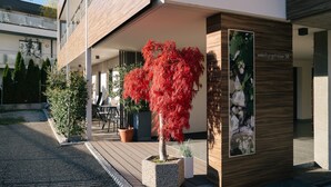 Un edificio moderno con fachada de madera, un árbol rojo en una jardinera y un letrero que dice 'Weinbergstrasse 58'.
