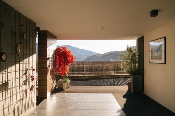 A room with a view of mountains, a tiled floor, and a wooden bench.