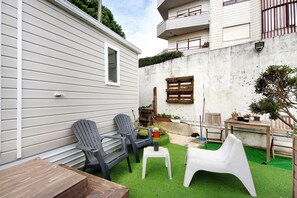 A patio with two Adirondack chairs, a small white table, and a wooden table. - Mobile Home "Villa Granja Sol 1" with Shared Garden & Wi-Fi (São Felix da Marinha)