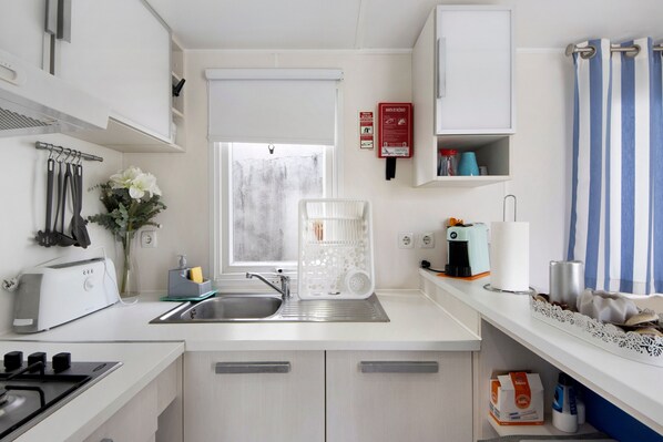 Cocina compacta con tostadora, pileta y ventana con persianas.