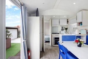 Cocina compacta con armarios blancos, encimera azul y un pequeño comedor.