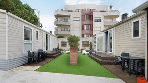 A courtyard with artificial grass, outdoor furniture, and a central planter. - Mobile Home "Villa Granja Sol 2" with Shared Garden & Wi-Fi (São Felix da Marinha)