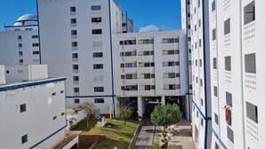 A modern building with multiple floors, a central courtyard with trees, and a clear blue sky. - Apartment "Clube Praia da Rocha 3" with Balcony & Wi-Fi (Portimao)