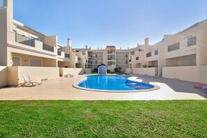 Un immeuble résidentiel doté d’une piscine centrale, de balcons et d’une pelouse bien entretenue.