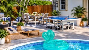 Un área de piscina con un flotador inflable, mesa de ping pong y mobiliario exterior.