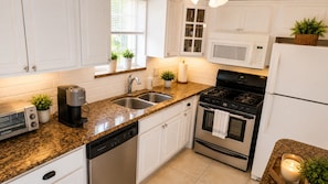 A modern kitchen with white cabinets, a granite countertop, a built-in microwave, a stainless steel stove, and a dishwasher. - Family Fun Villa | Heated Pool | Arcade & Ping Pong | BBQ | Near Hollywood Beach (Hollywood)