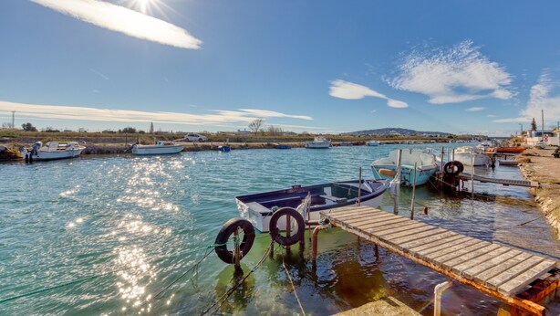 A calm harbor with boats docked, a wooden pier, and a clear sky.