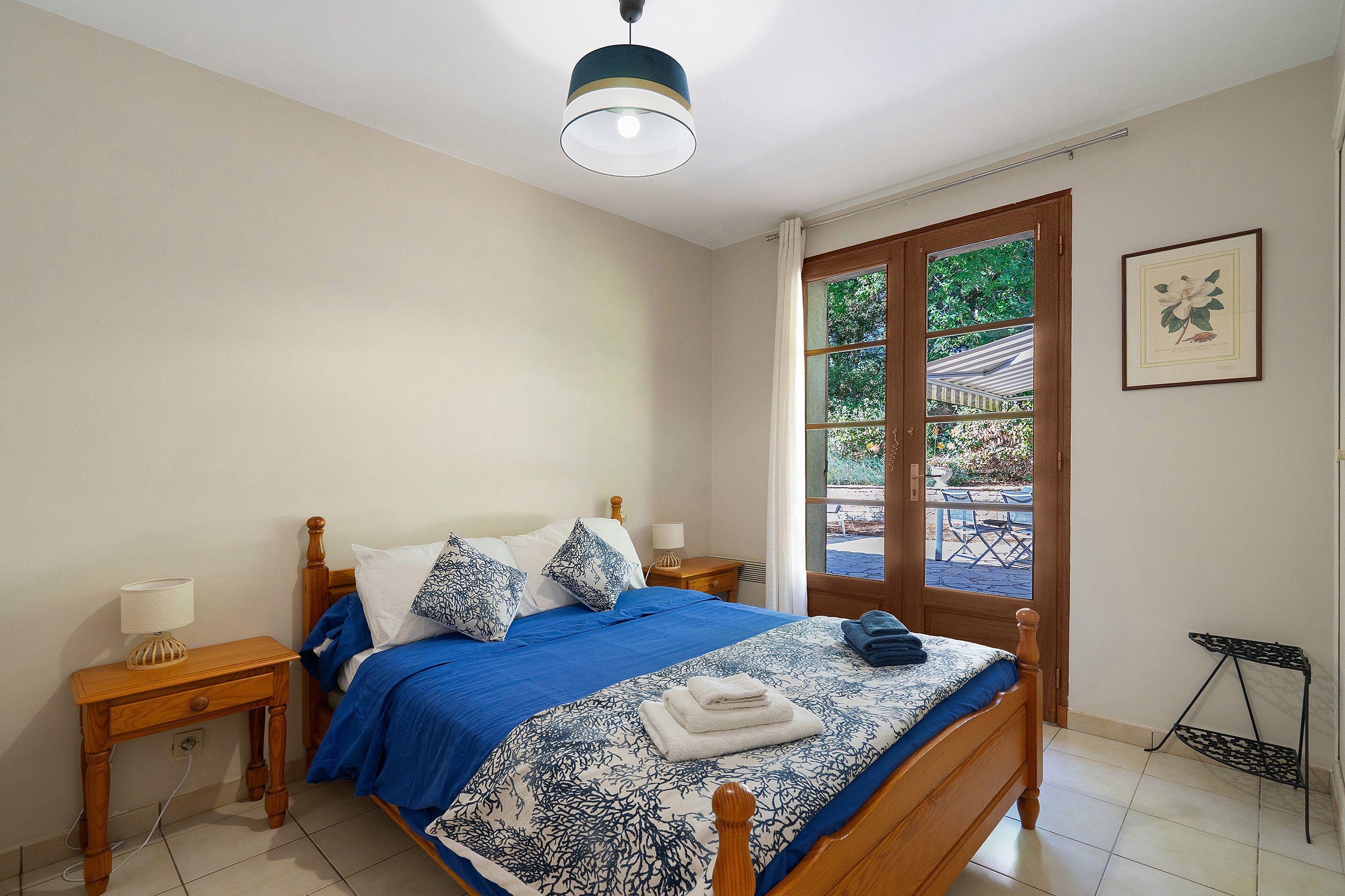 Une chambre à coucher avec un lit, des tables de chevet, une fenêtre donnant sur un beau paysage et un tableau encadré au mur.
