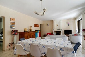 Ein Essbereich mit einem Tisch, der mit einer Tischdecke mit Meeresmotiven bedeckt ist, umgeben von Stühlen.