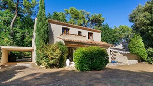 Una casa a due piani con tetto in tegole, un portico coperto e un giardino curato.