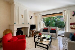 A living room with a fireplace, television, and seating area with a view to the outdoors.