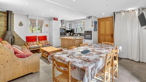 Een moderne keuken met een centraal eiland, houten meubels en een eethoek met een tafel voor vier personen.