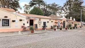 Un bâtiment sur lequel on peut lire l’inscription « Jóias Sintra », une rue pavée et des tables installées à l’extérieur, agrémentées de plantes en pot.