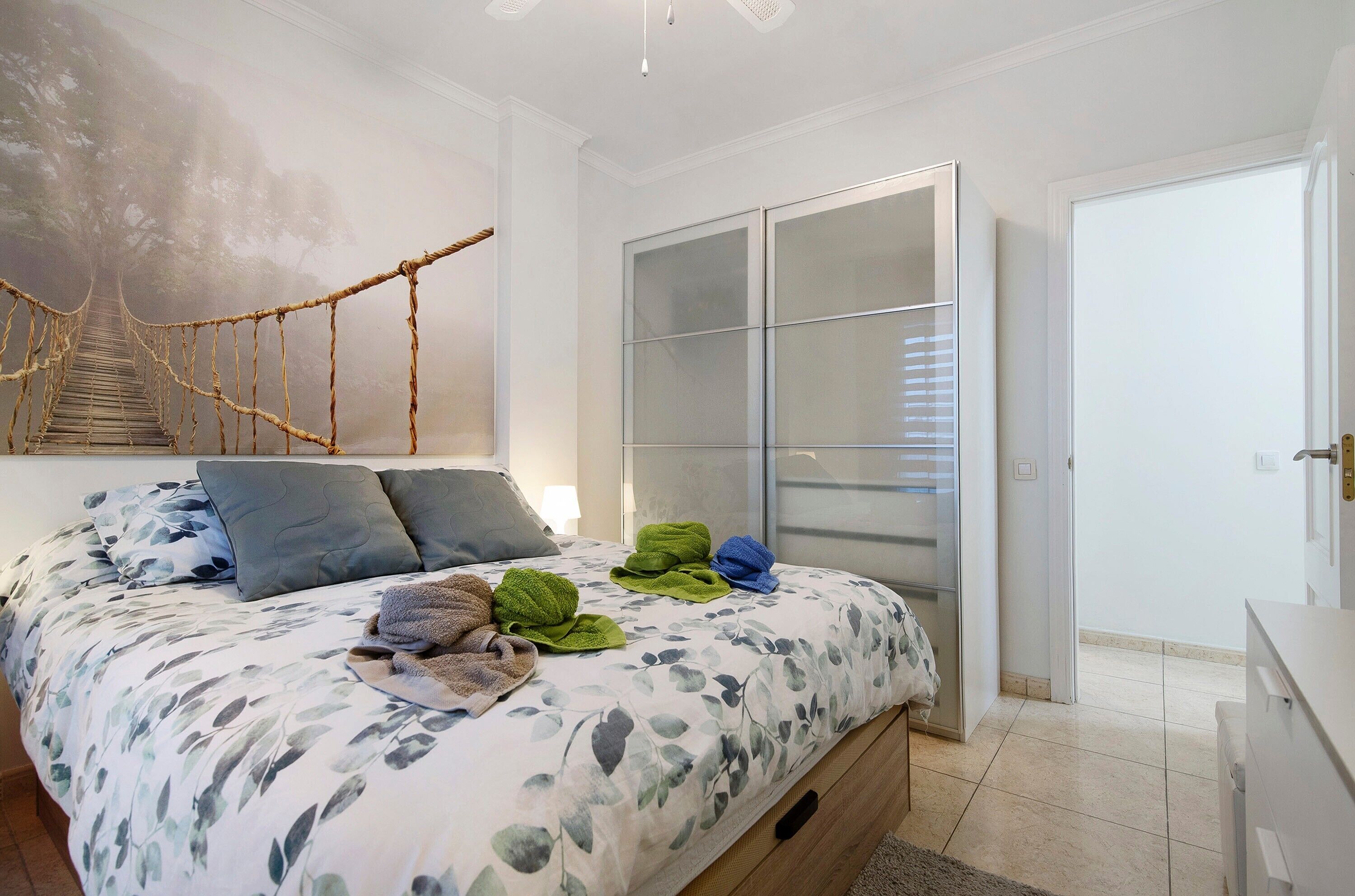 Ein Schlafzimmer mit Bett, großem Fenster, Kleiderschrank und Treppe mit Seilabsperrung.