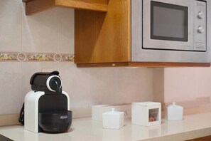 Uma cozinha com micro-ondas, máquina de café e um refrigerador pequeno.