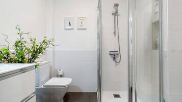 A modern bathroom with a toilet, shower, and two framed pictures on the wall.