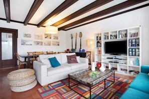 A living room with a white sofa, a coffee table, a bookshelf, and a television.