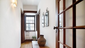 A hallway with a wooden bench, a large vase, and a door with a mirror. - Vacation Home "São Martinho All The Best" with Sea View, Shared Pool & Wi-Fi (São Martinho do Porto)