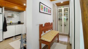 Una cocina con armarios blancos, techo de madera y un banco con cojín estampado.