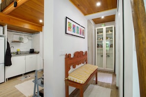 A kitchen with white cabinets, a wooden ceiling, and a bench with a patterned cushion.