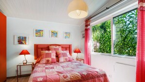 Un dormitorio con cama, dos mesitas de noche, una ventana con cortinas y decoración en la pared.