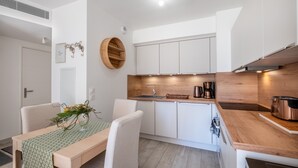 A modern kitchen with white cabinets, a wooden countertop, and a built-in stove. - Apartment 'Le Jasmin' with Private Terrace, Wi-Fi and Air Conditioning (Nice)