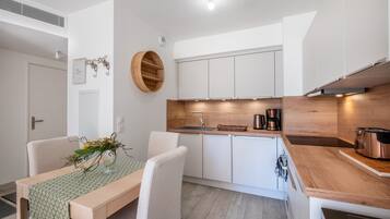 Una cucina moderna con mobili bianchi, un piano di lavoro in legno e un piano cottura integrato.