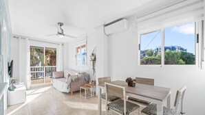 A bright, modern room with a dining area, a sofa, and a view of the city.