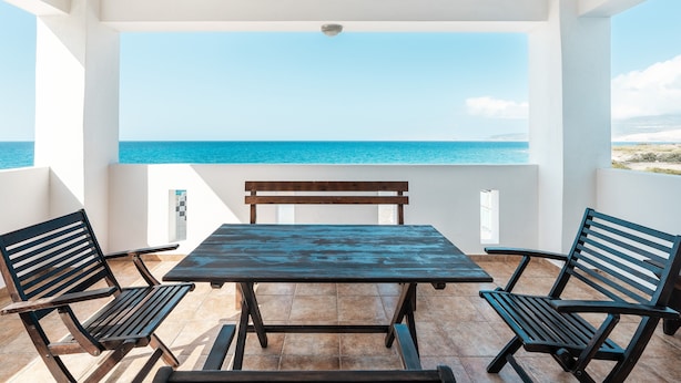 Ein Balkon mit Tisch und Stühlen mit Blick auf ein Gewässer.