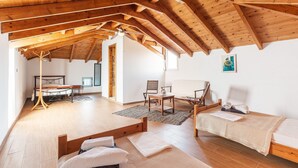 A room with a sloped wooden ceiling, two beds, a chair, a table, and a hanging light fixture. - Country House 'White Pearl Apolakkia 2' with Shared Pool, Shared Terrace and Wi-Fi (Rhodes)