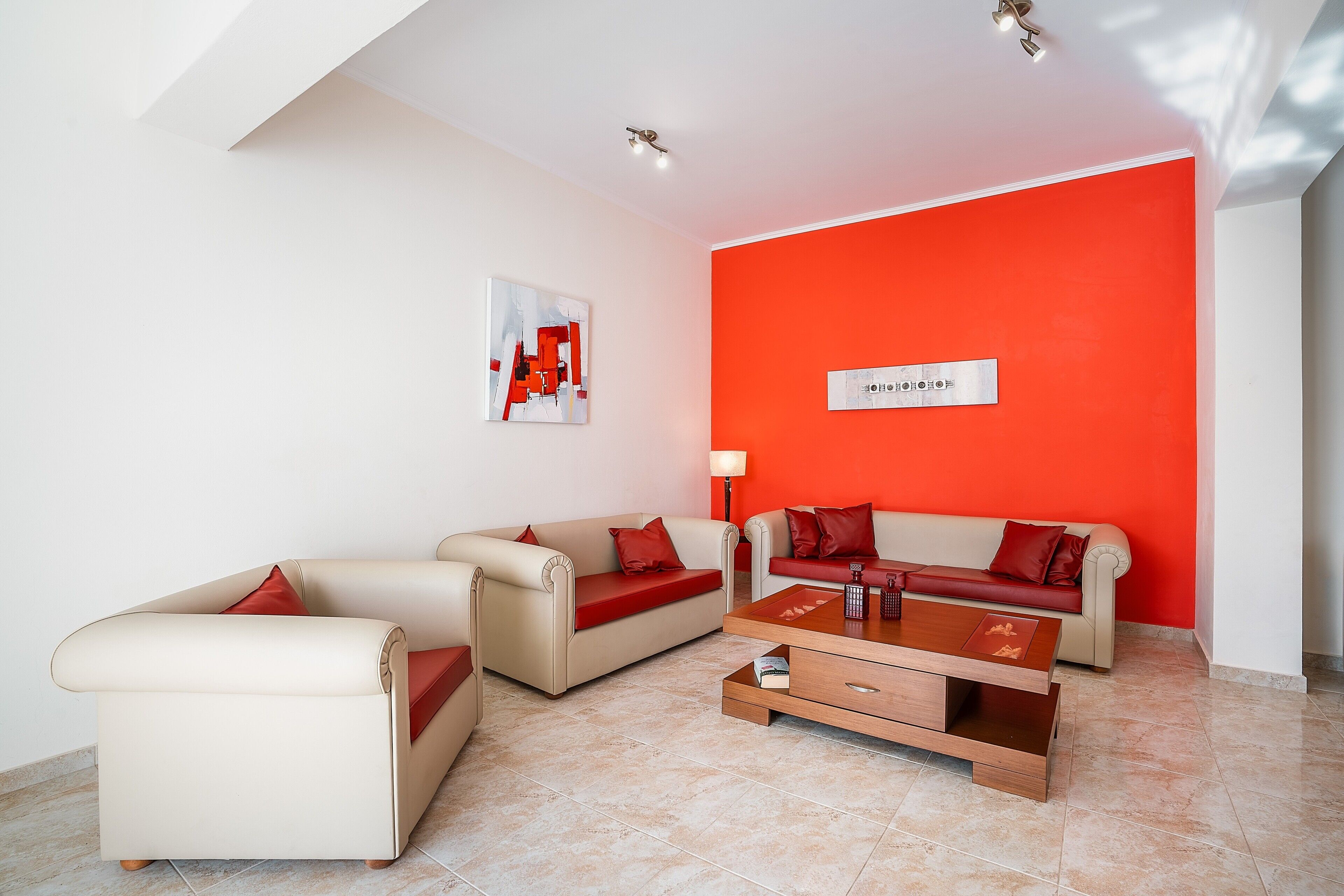 A modern living room with two sofas, a coffee table, and a red accent wall.