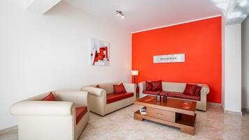 A modern living room with two sofas, a coffee table, and a red accent wall.