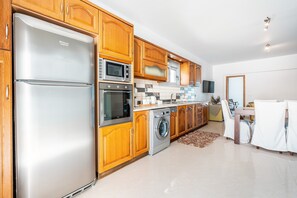 Una cucina moderna con mobili in legno, elettrodomestici in acciaio inossidabile, una lavatrice e un'area pranzo con sedie.