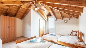 Een slaapkamer met twee houten bedden, een garderobe en een plafondventilator.
