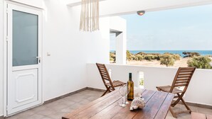 Ein Balkon mit Holztisch, zwei Stühlen, einer Flasche und einem Glas.
