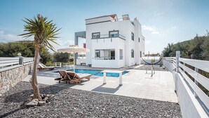 Un bâtiment moderne à deux étages, doté d’une piscine, d’un espace extérieur aménagé et d’une clôture blanche.