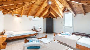 Une pièce avec un plafond en bois incliné, deux lits, une chaise, une armoire et une porte.